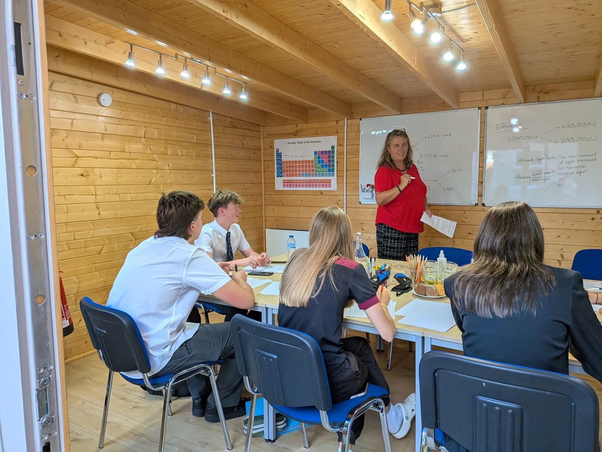A tutor teaching a small group of students in the log cabin classroom